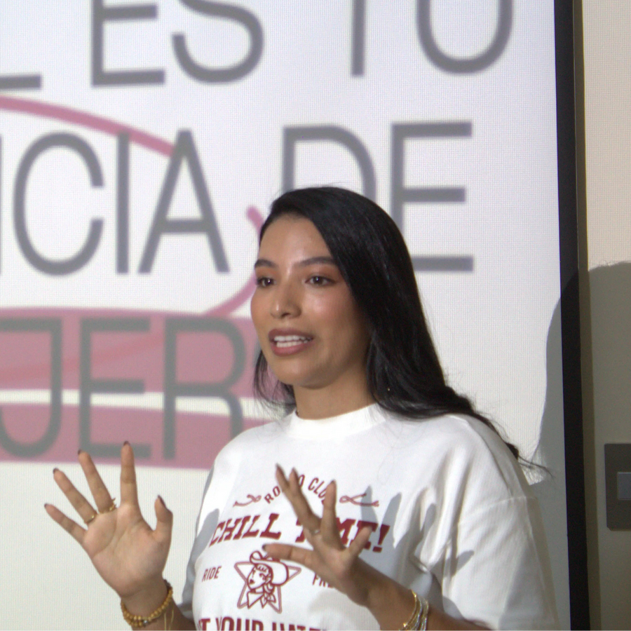 Woman speaking in front of a screen with text in Spanish